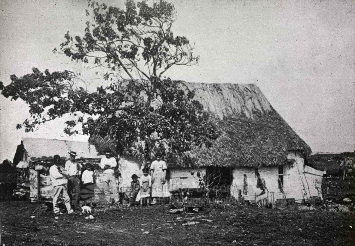 A family standing outside a thatched bohío in the Cuban countryside