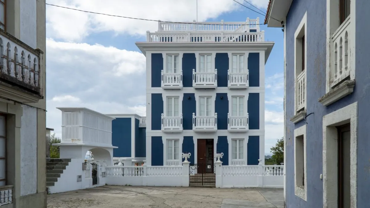 A blue and white indiano house with glazed galleries and a rooftop balustrade